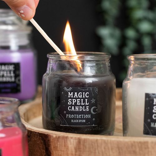Hand lighting a black Opium protection spell candle jar for spiritual rituals at Kimchi Toki shop