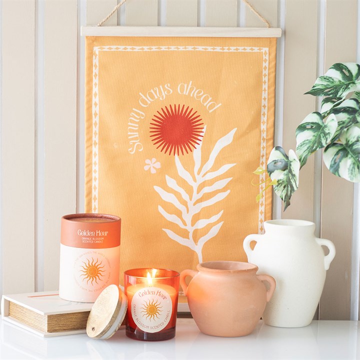 Terracotta urn candle displayed with a vibrant wall hanging and decorative plants at Kimchi Toki store