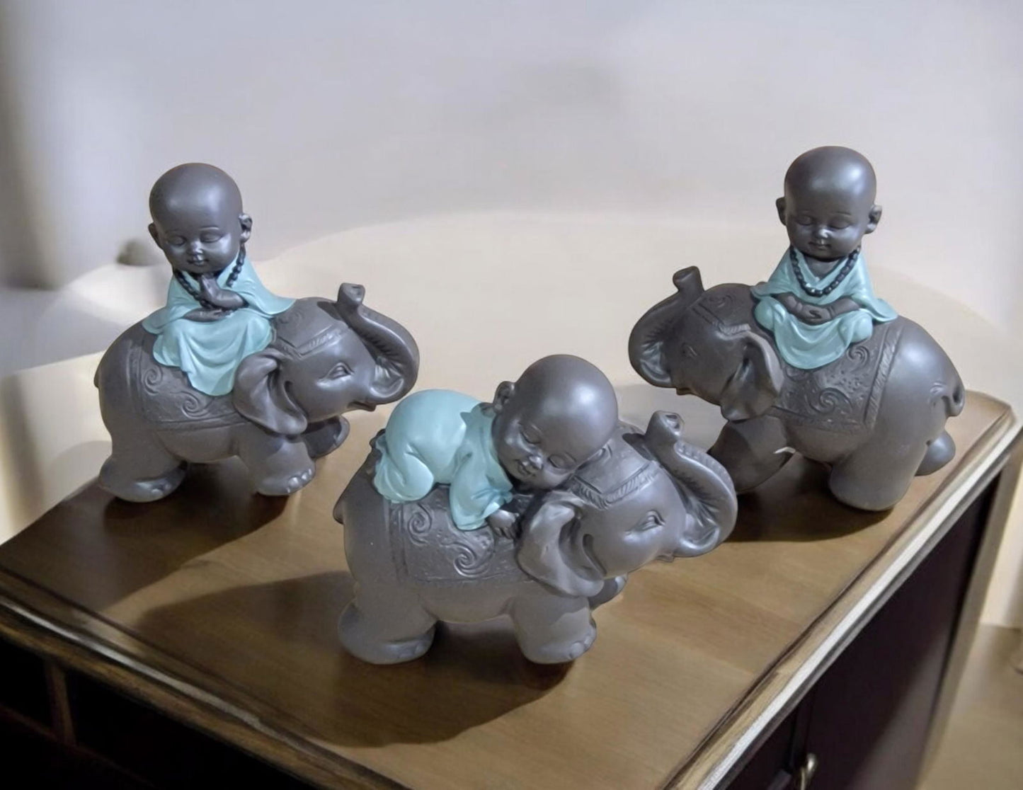 Geko Products Buddha elephant figurines showing three gray elephants with small meditating children in blue robes