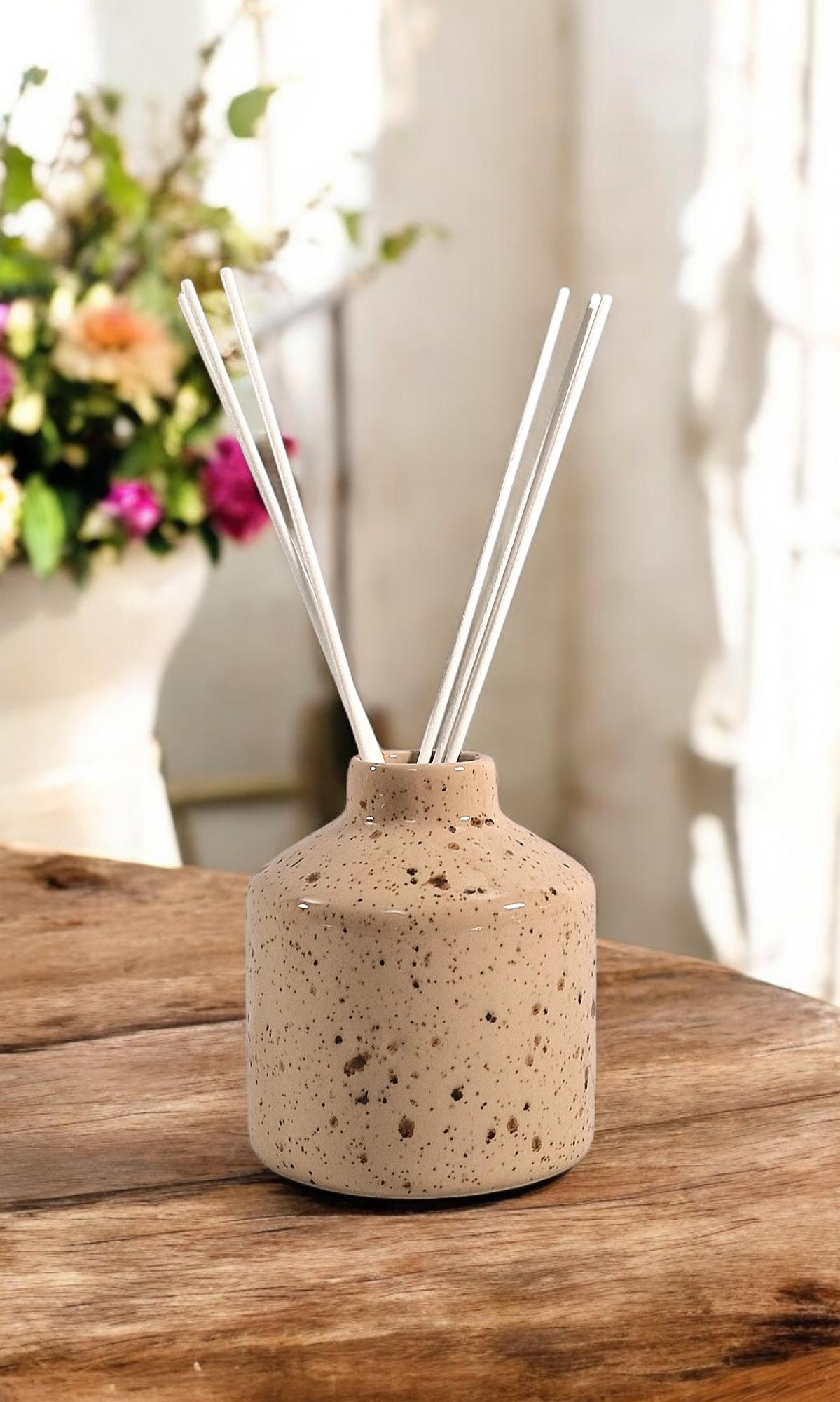 Geko Products ceramic diffuser cedar cotton with reed sticks in speckled brown jar on wooden table