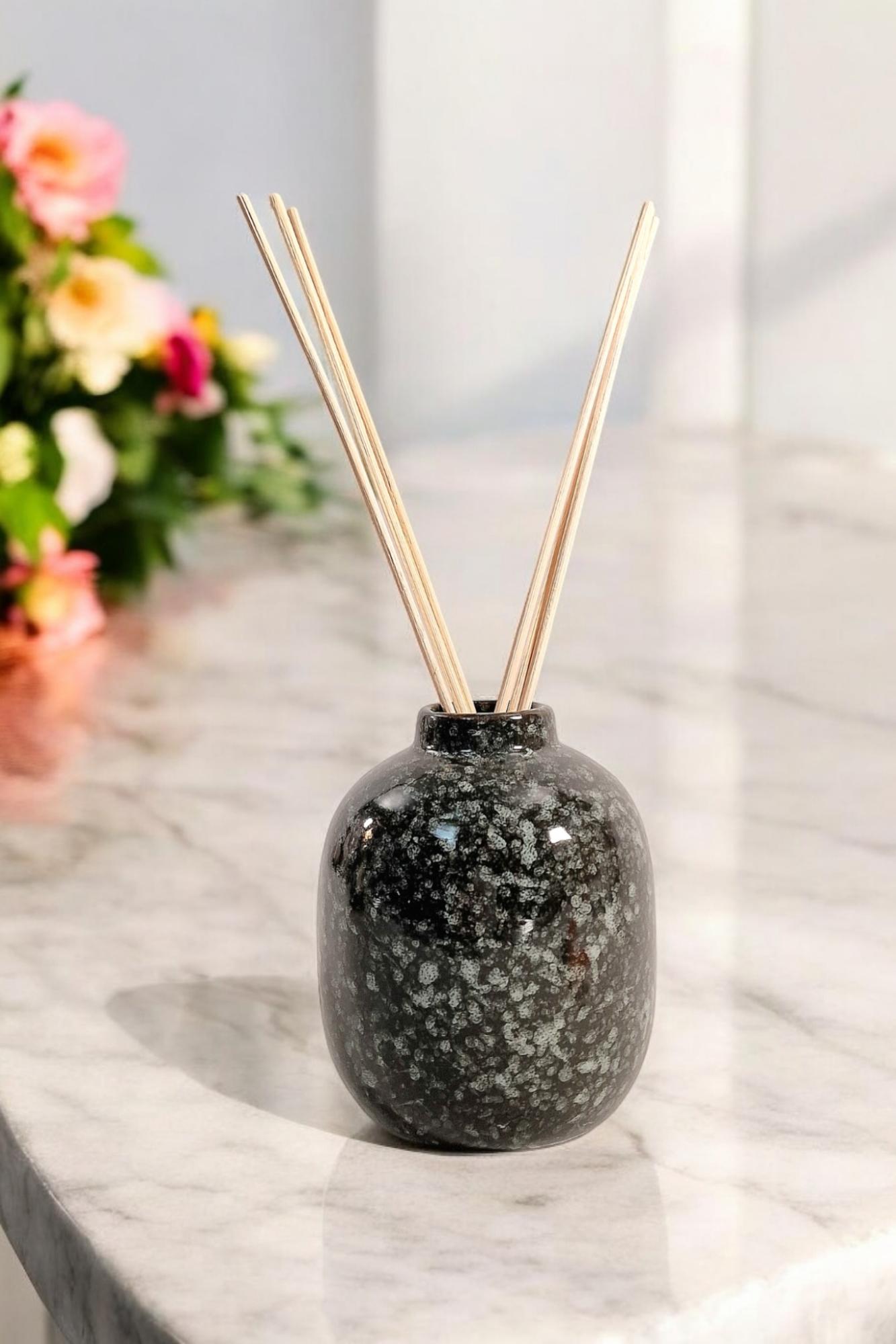 Geko Products ceramic diffuser wild fig black and gray speckled vase with reed sticks on marble surface