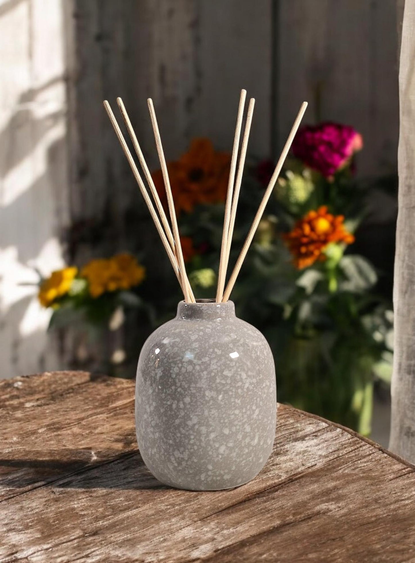 Geko Products ceramic diffuser wild pear patchouli with gray speckled finish and wooden reeds on wooden table