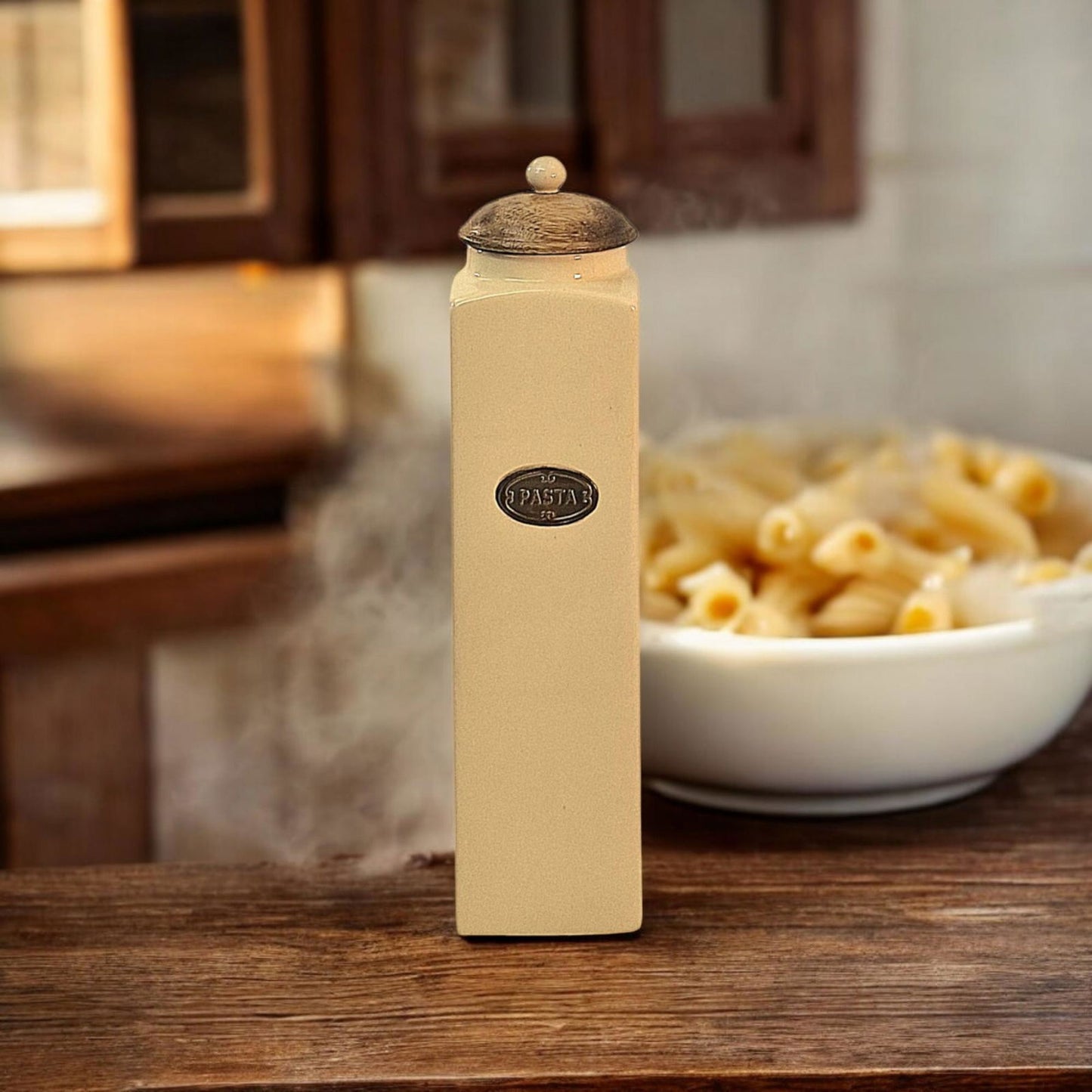 Geko Products beige ceramic pasta jar with wooden lid on wooden table next to bowl of cooked pasta