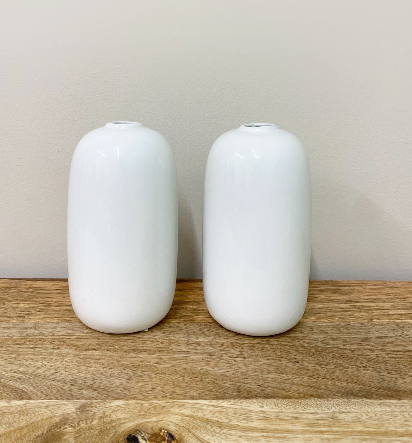 Minimalist white ceramic vases with face design by Geko Products on wooden surface