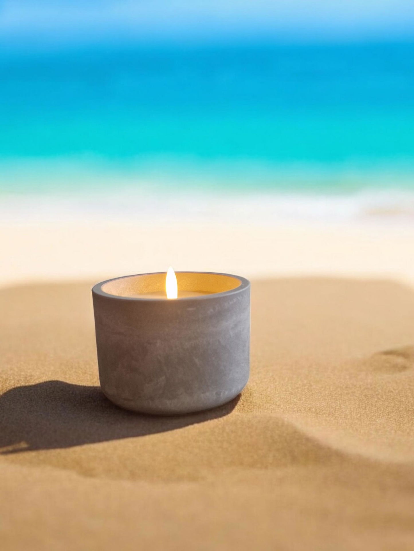 Circular LED cement candlepot by Geko Products glowing on sandy beach with ocean background
