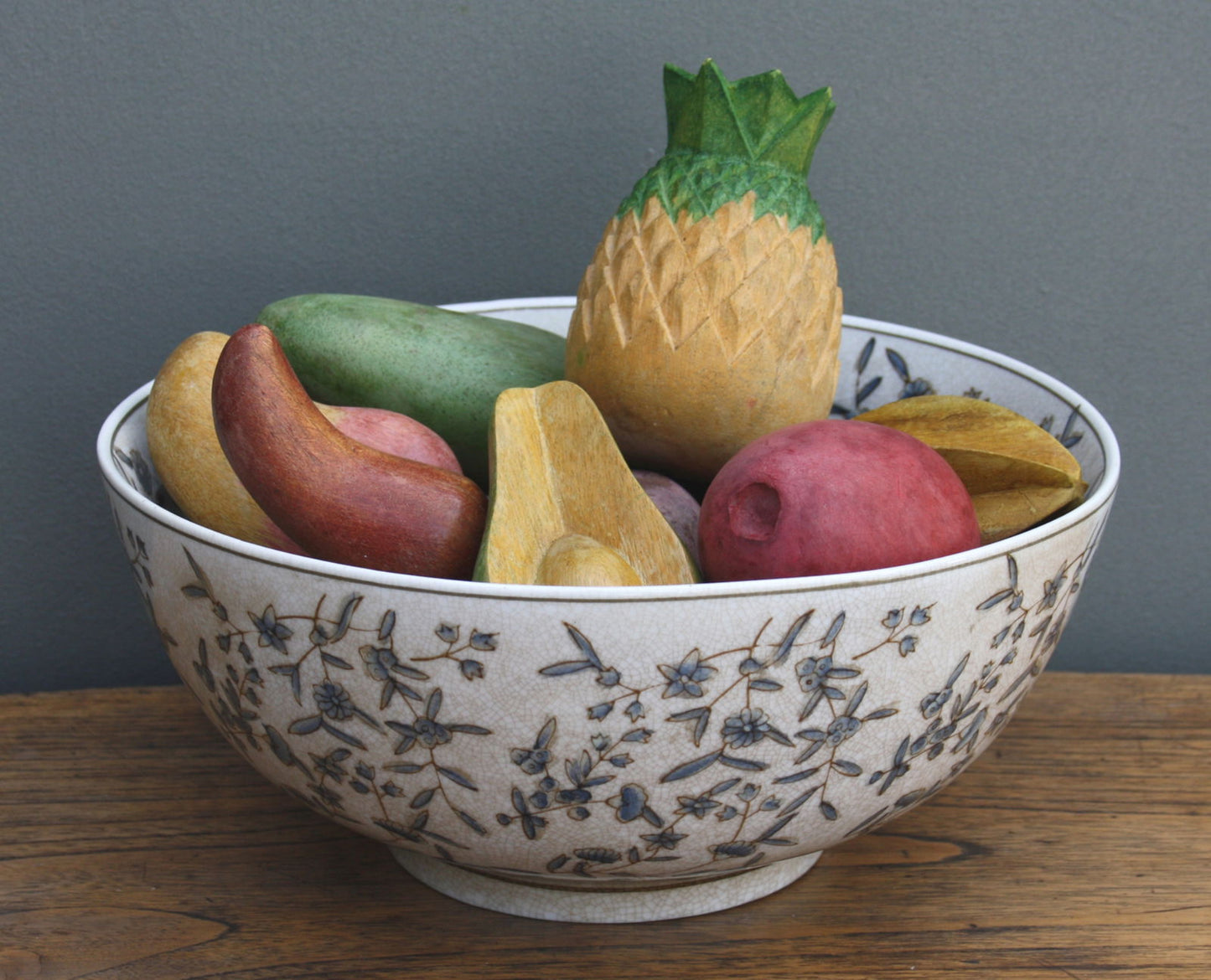 Geko Products ditsy print ceramic bowl filled with decorative wooden fruits on wooden surface