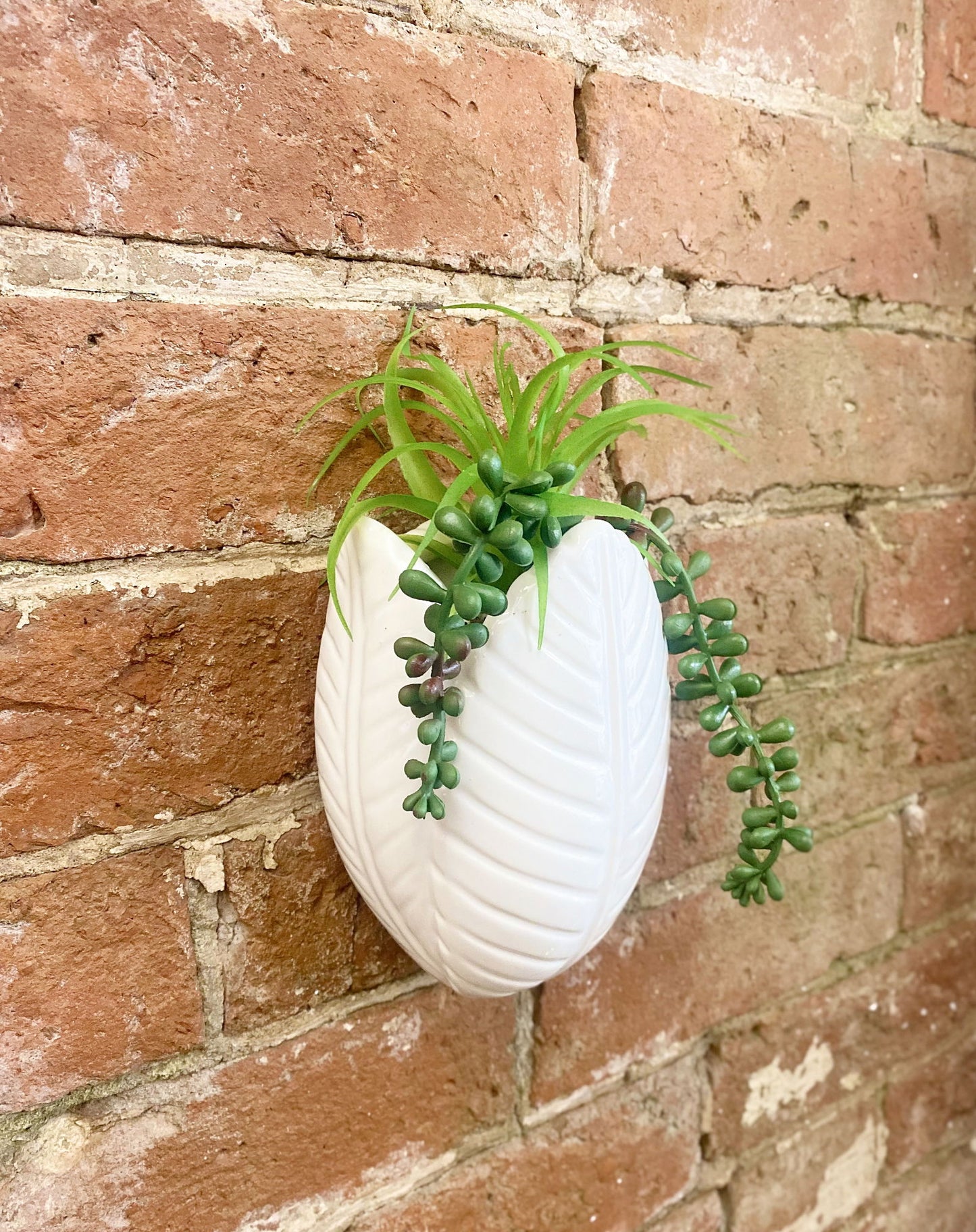 Geko Products white leaf-shaped wall planter with faux succulents wall decor on brick background