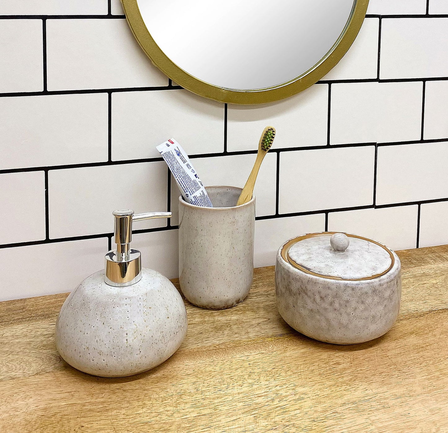 Taupe ceramic pot with lid by Geko Products on wooden countertop with matching soap dispenser and toothbrush holder