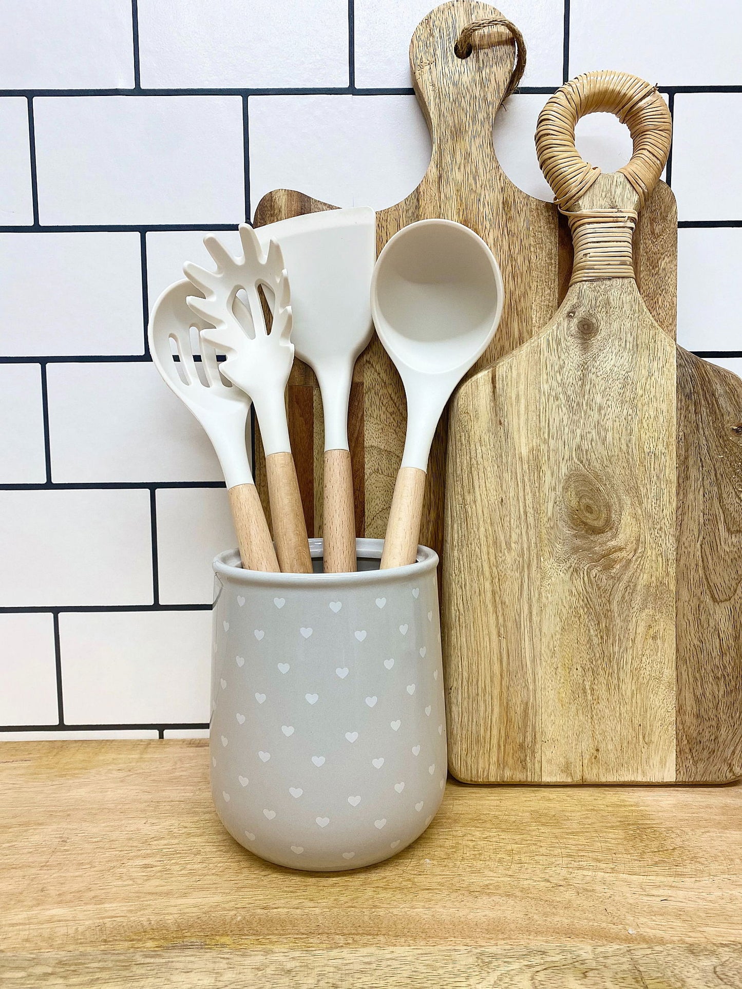 Hearts design utensil holder with wooden handle kitchen utensils on wooden countertop