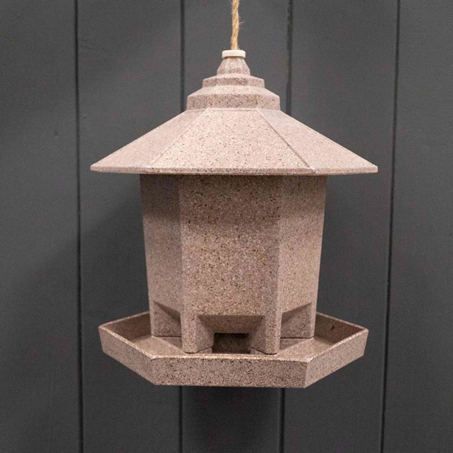 Geko Products hexagonal bird feeder in natural stone color hanging against dark background