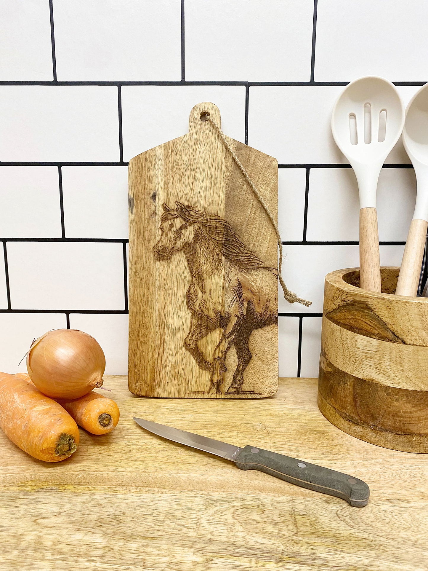 Horse engraved cheese board by Geko Products on kitchen counter with vegetables and utensils