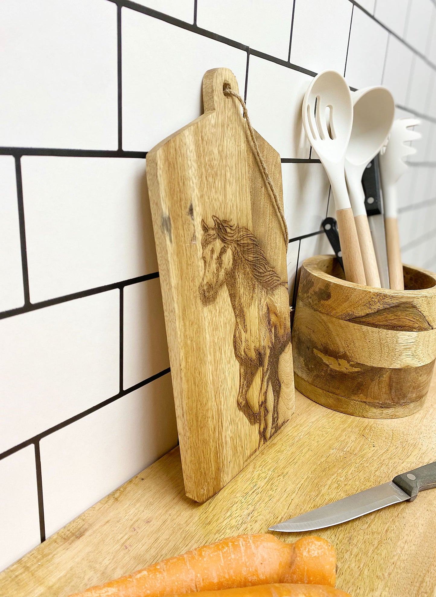 Horse engraved cheese board by Geko Products displayed on kitchen counter with wooden utensils and carrots