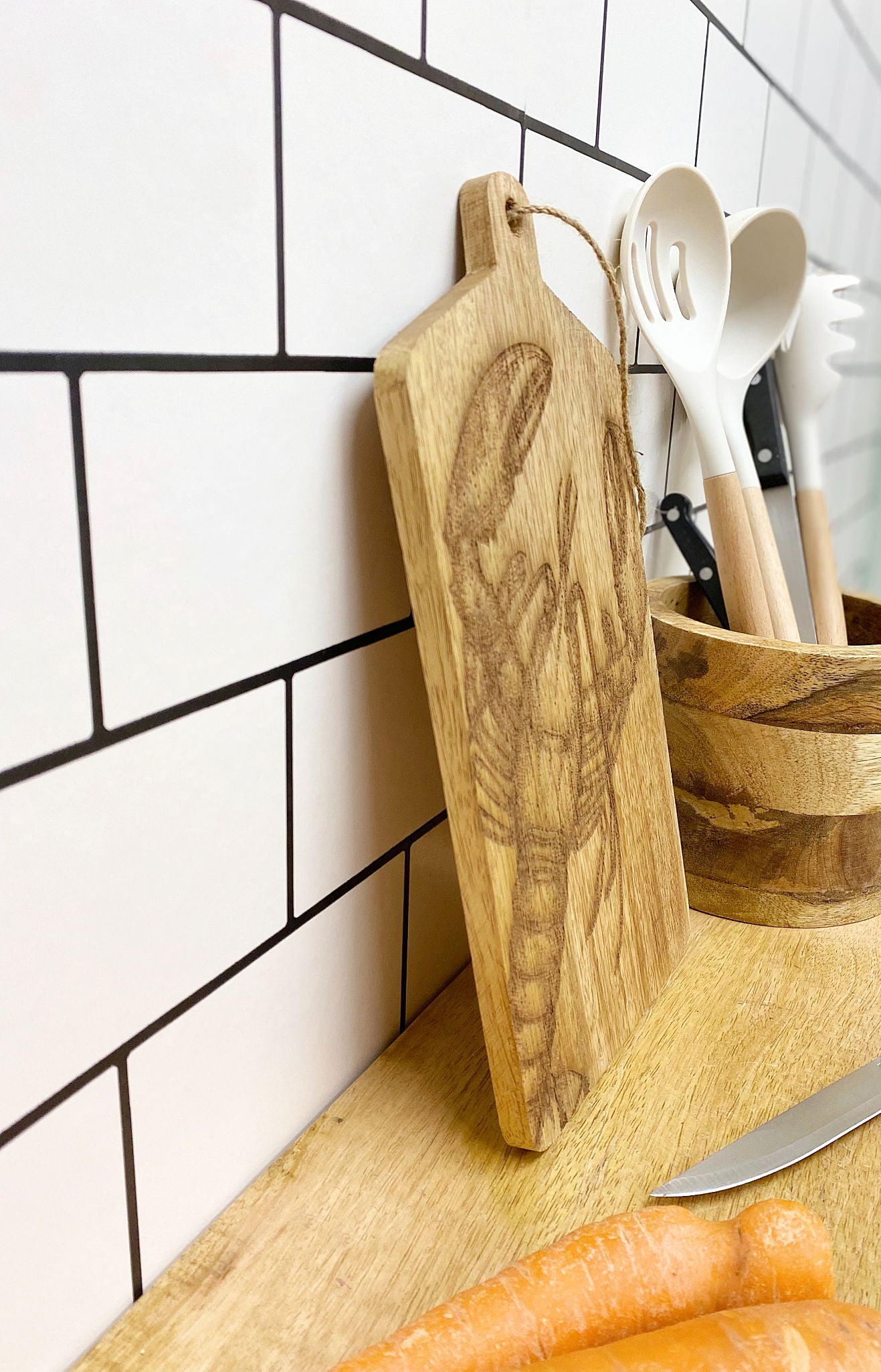 Geko Products wooden lobster cheese board with engraved lobster design leaning against a tiled kitchen wall