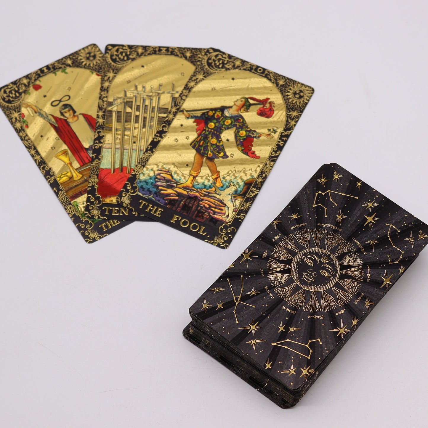 Luxury tarot deck with guidebook featuring gold foil cards depicting The Fool and The Ten of Swords