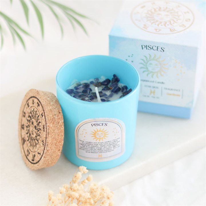 Pisces gardenia candle in a blue container with gemstone accents, placed beside its decorative box