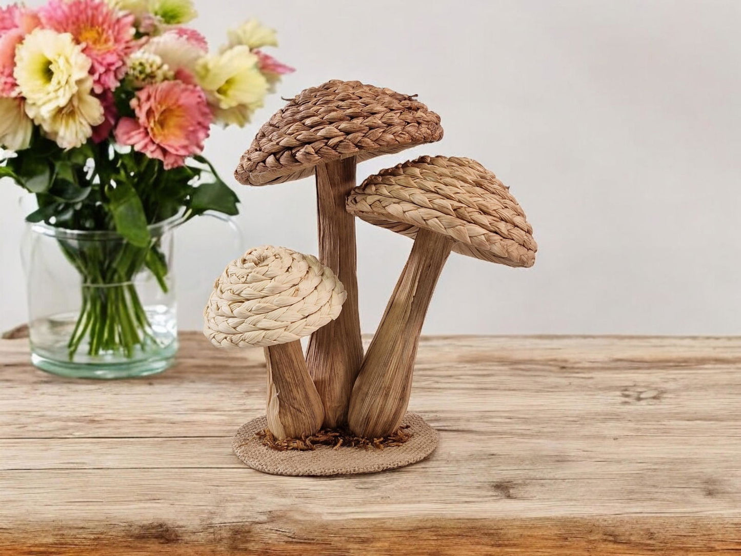 Geko Products rattan mushroom ornament with three woven mushrooms on wooden surface next to flower vase