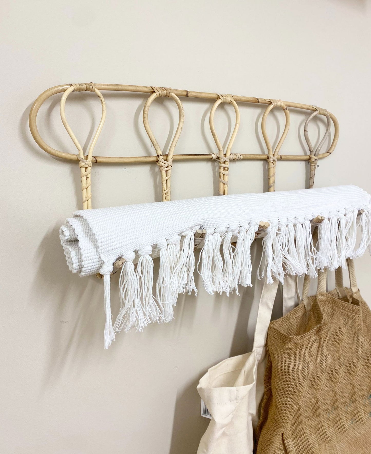 Geko Products rattan wall hooks mounted on wall holding white fringed cloth and bags