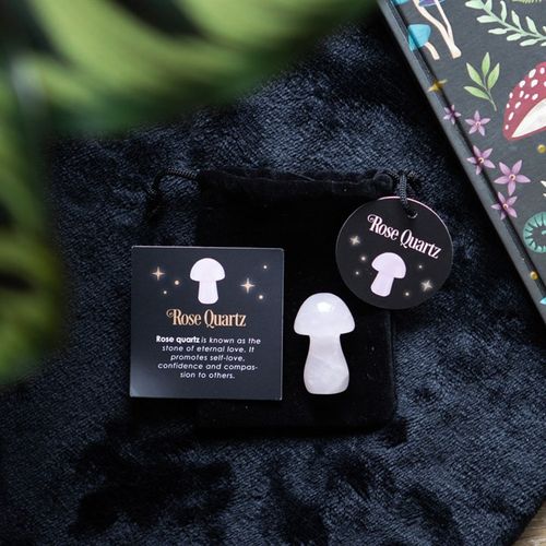 Rose quartz crystal mushroom on a black pouch with informational card about rose quartz properties