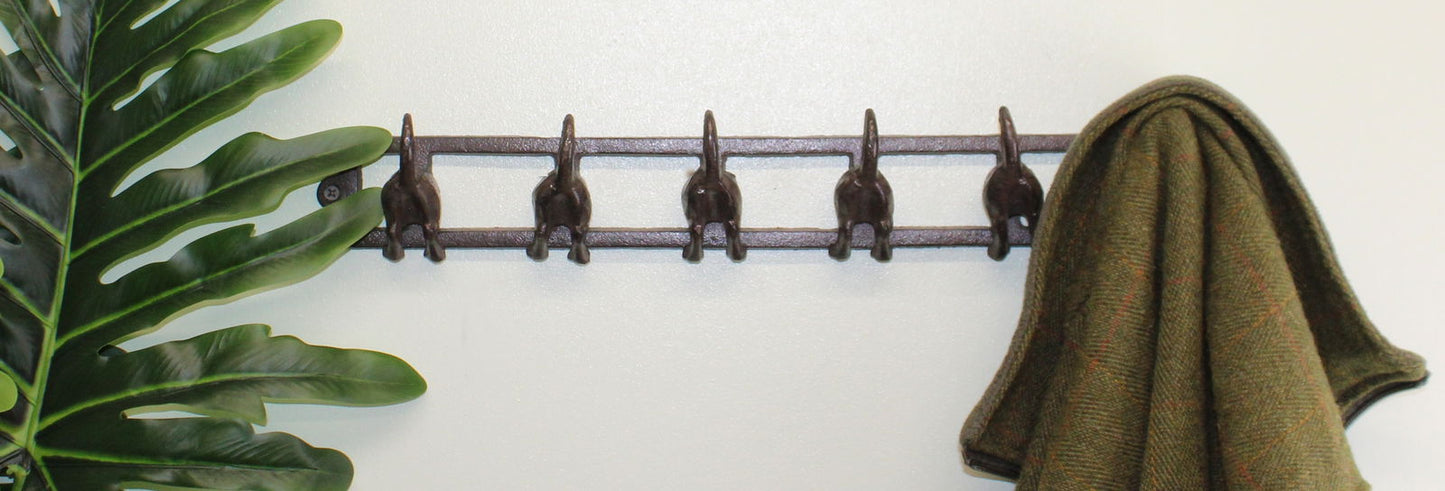 Geko Products rustic dog tail wall hooks metal rack with five hooks holding a coat on a white wall
