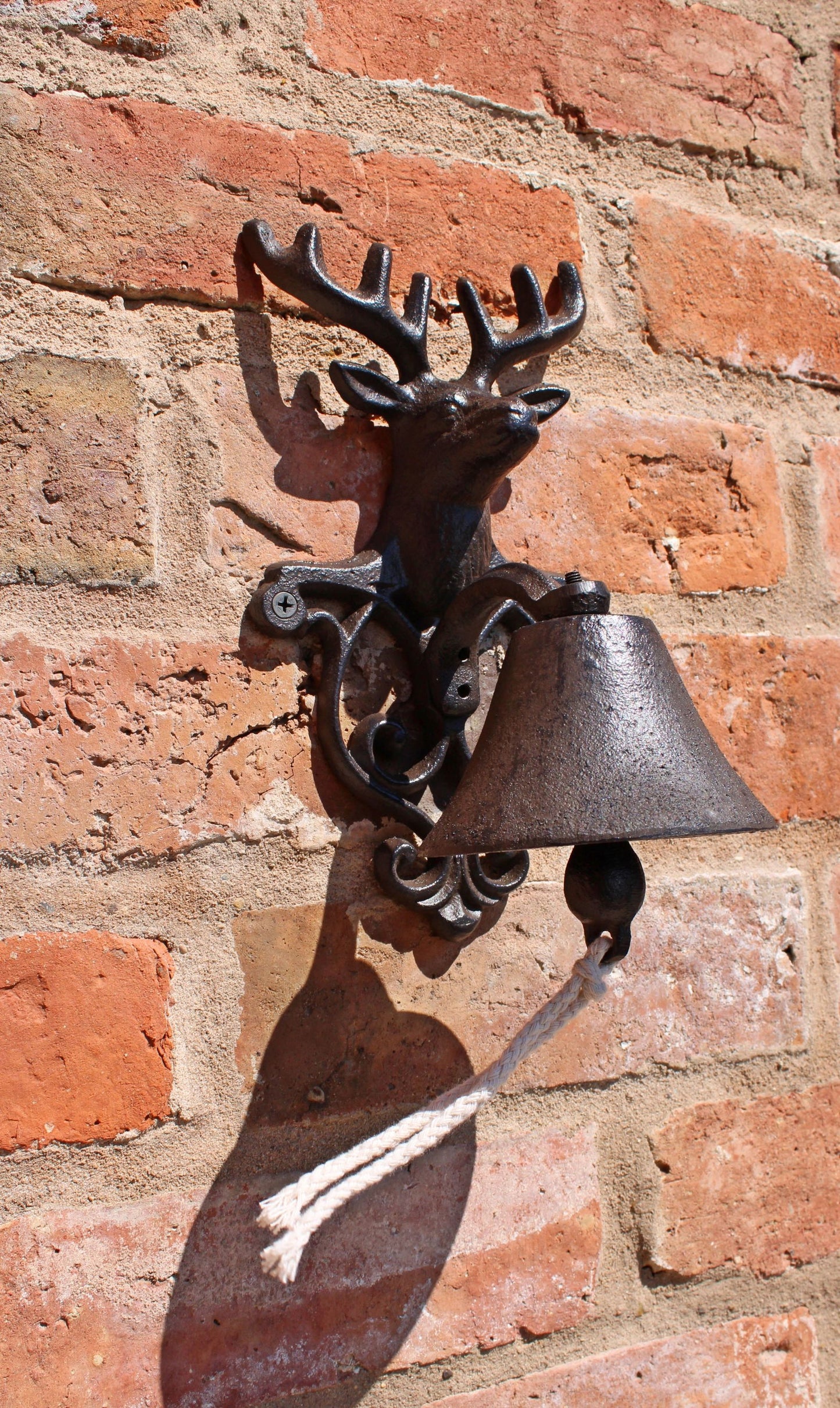 Rustic reindeer wall bell by Geko Products mounted on a brick wall with a metal pull rope