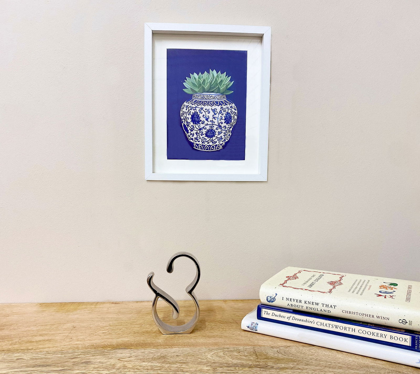 Geko Products silver ampersand home decor sculpture on wooden table with blue vase art and stacked books