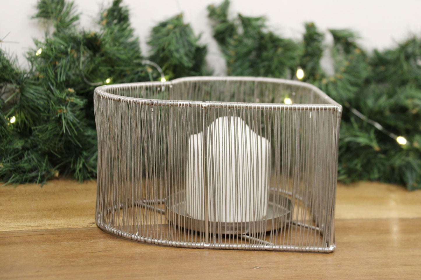 Geko Products silver heart tealight holder with vertical wire design holding white candle on wooden surface