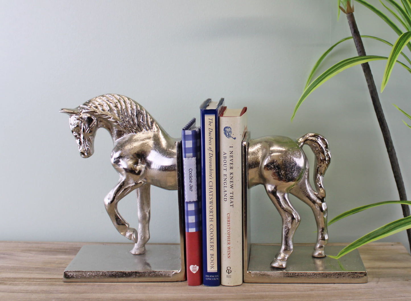 Silver horse bookends by Geko Products holding a set of books on a wooden surface