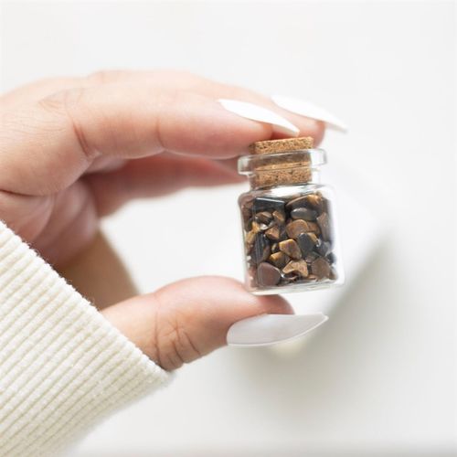 Small glass jar of Tiger's Eye crystals held in hand, ideal for a spiritual healing crystals jar