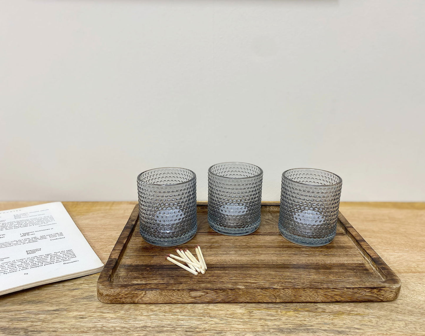 Geko Products set of three gray spiritual tea light holders on wooden tray with matches and book