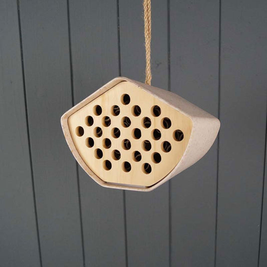 Geko Products sustainable bee house with multiple holes hanging against gray wooden background