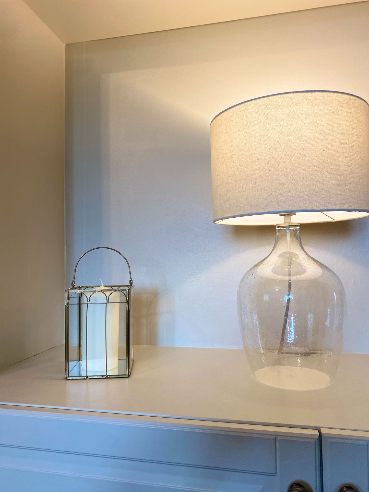Mirrored candle lantern decor from Geko Products displayed on a white cabinet next to a glass table lamp