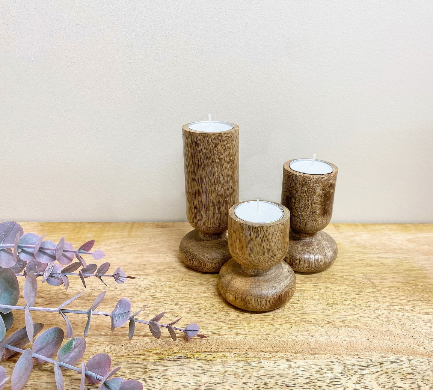 Geko Products wooden candlestick set featuring three natural wood holders with white candles on wooden surface