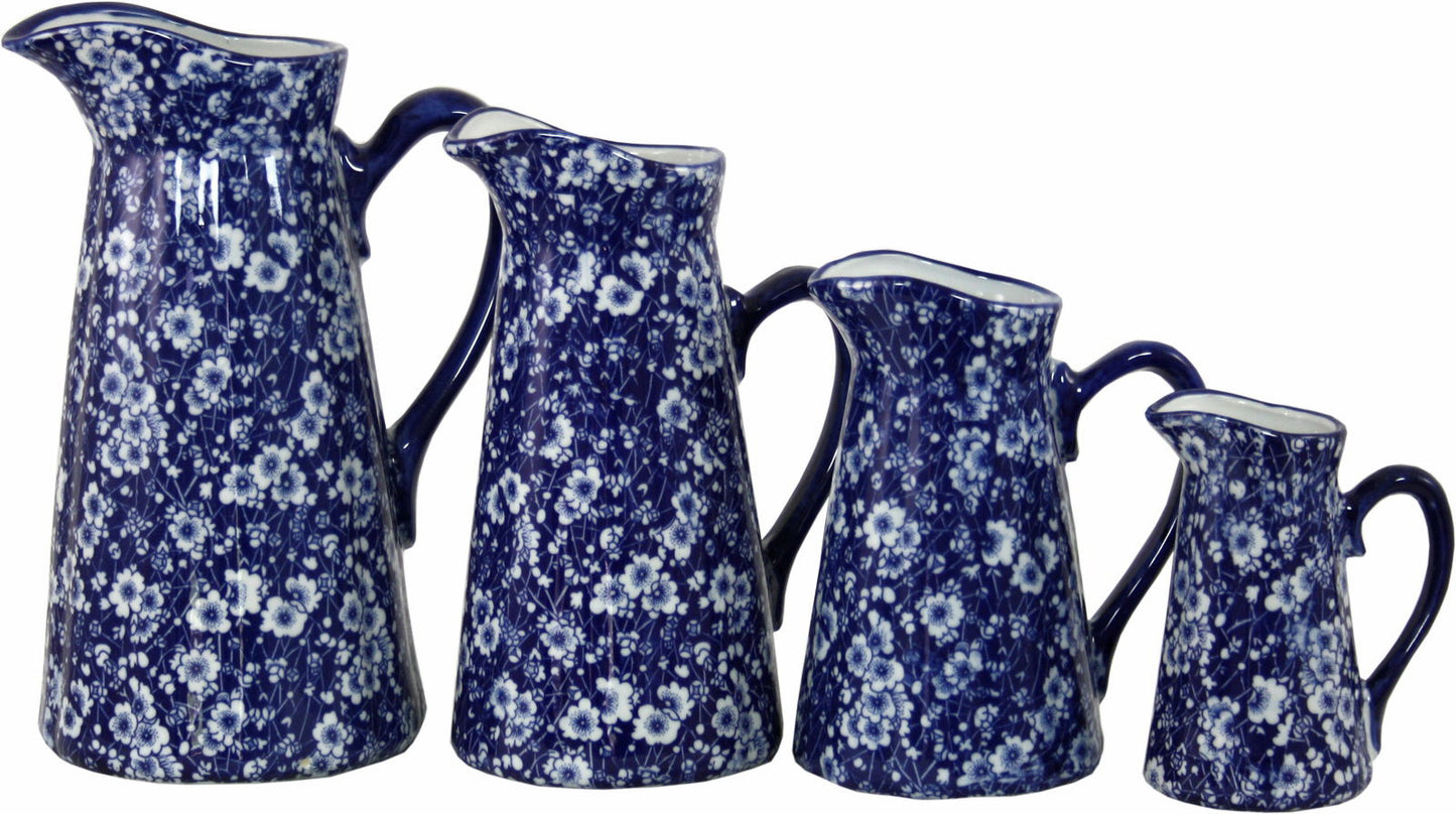 Set of four vintage ceramic jugs set in blue with white floral patterns and varying sizes