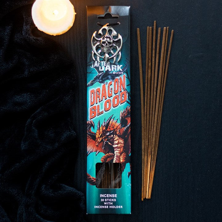 Dragon Blood incense sticks with a decorative holder, featured on a black surface with a lit candle for a serene ambiance