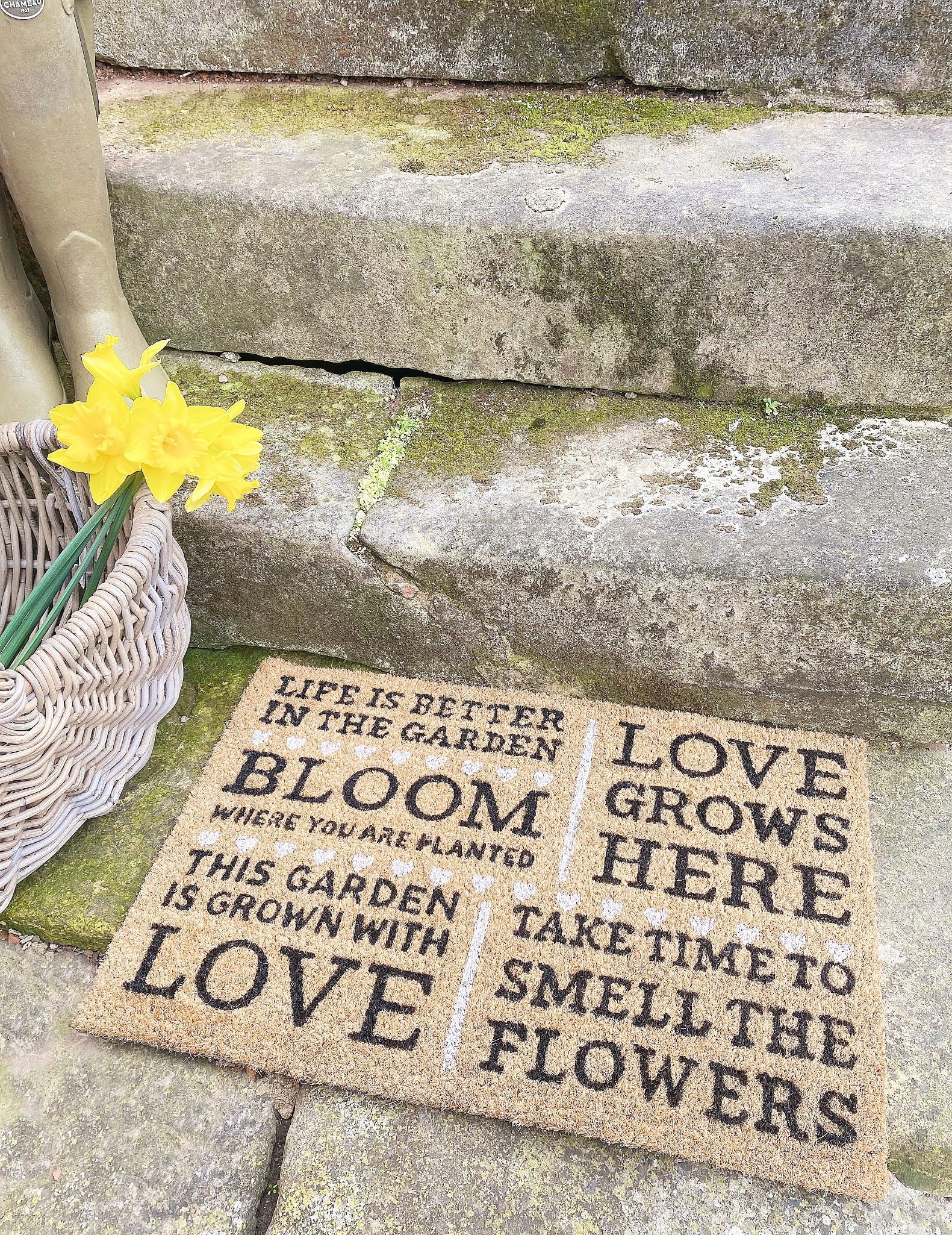 Geko Products bloom potting shed doormat with garden quotes placed on stone steps next to basket and yellow flowers