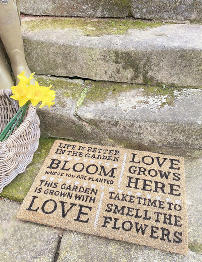 Geko Products bloom potting shed doormat with garden quotes placed on stone steps next to basket and yellow flowers