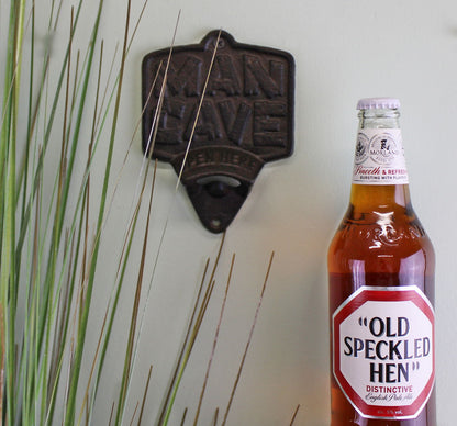 Geko Products cast iron bottle opener wall mount with rustic design on white wall next to a brown Old Speckled Hen beer bottle