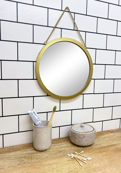 Taupe ceramic pot with lid on wooden countertop next to matching toothbrush holder in modern bathroom