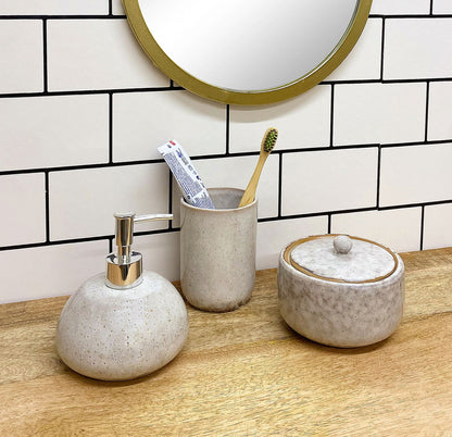 Taupe ceramic pot with lid by Geko Products on wooden countertop with matching soap dispenser and toothbrush holder