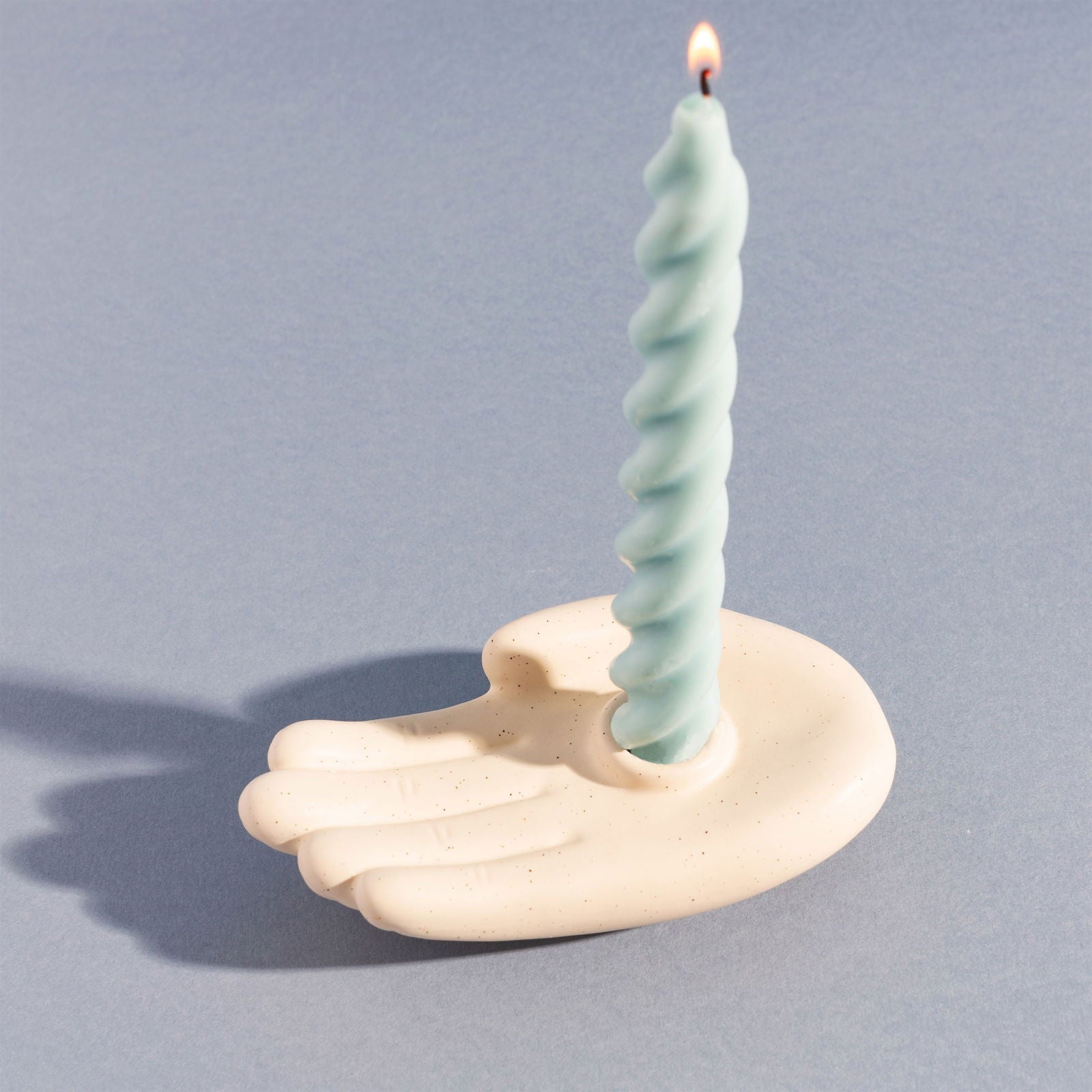 Geko Products hand-shaped candle holder in cream color holding a twisted blue candle