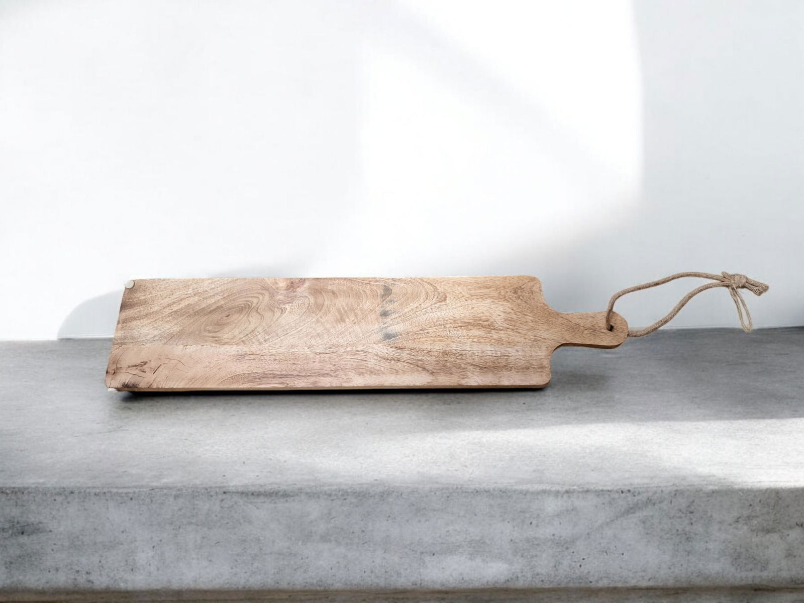 Geko Products mango wood chopping board with handle and leather hanging strap on concrete surface