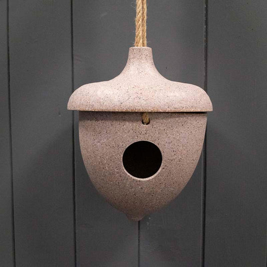 Natural acorn birdhouse by Geko Products hanging with rope against dark wooden background