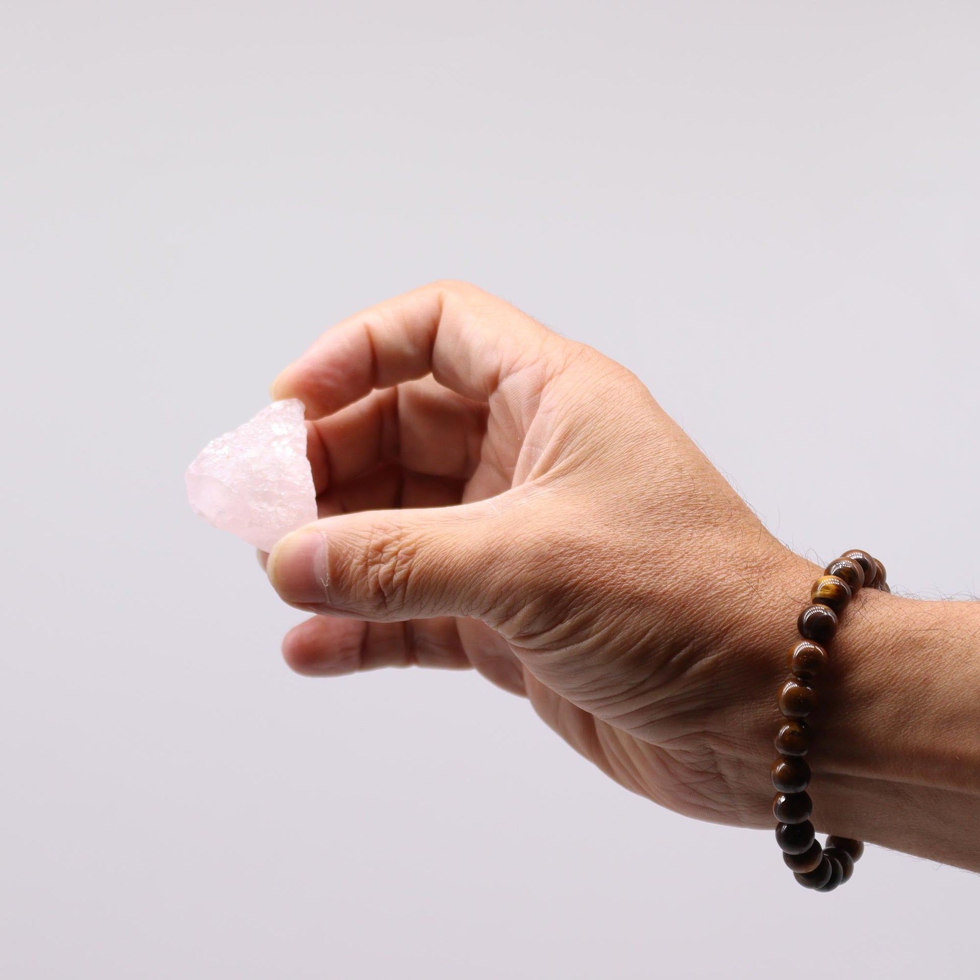 Hand holding a raw rose quartz crystal showcasing its natural colour and texture for healing and decoration