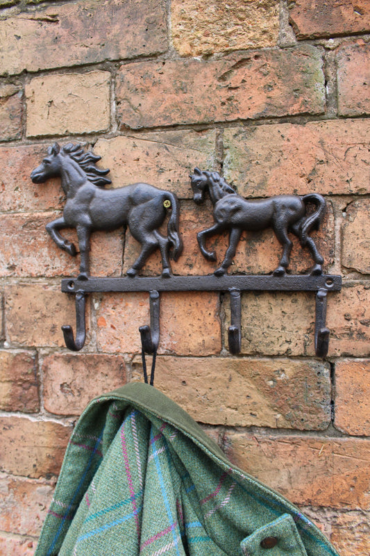 Rustic Cast horse wall hooks mounted on brick wall holding a green plaid blanket