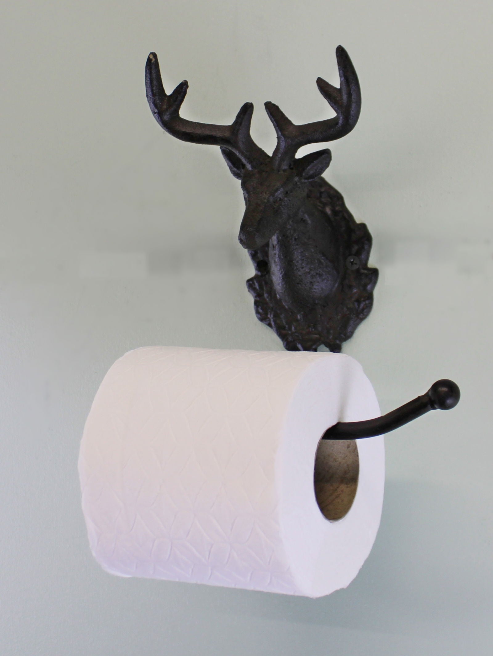 Rustic stag head toilet roll holder in dark metal mounted on wall with white toilet paper roll