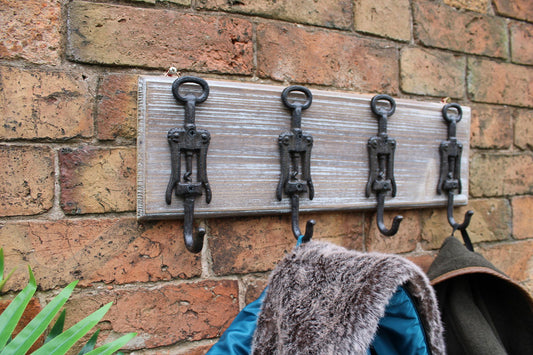 Rustic wall hooks cast iron mounted on wooden board with coats hanging on brick wall